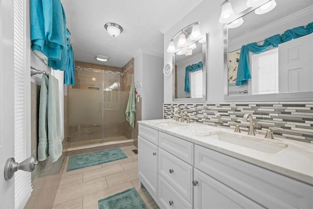 bathroom with tile patterned floors, backsplash, crown molding, a shower with door, and vanity