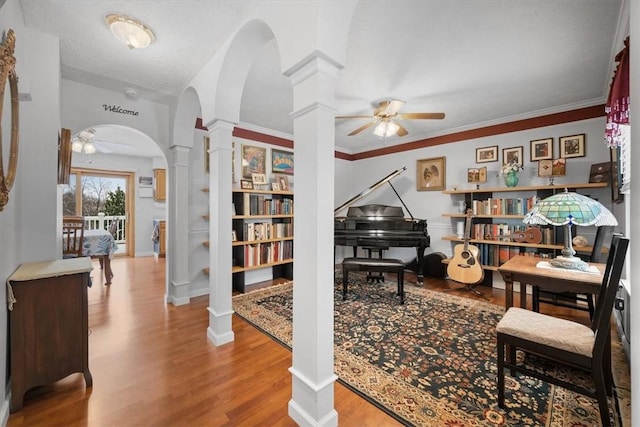 interior space with decorative columns, ceiling fan, hardwood / wood-style floors, and a textured ceiling