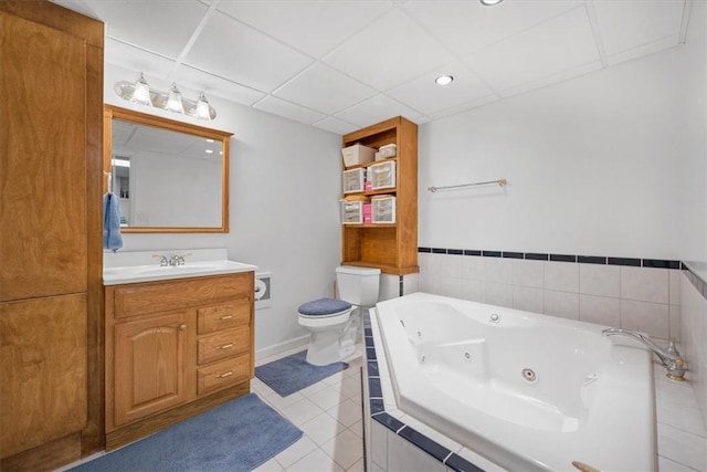 bathroom featuring tile patterned flooring, vanity, toilet, and tiled bath