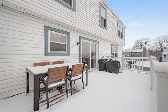 snow covered patio featuring area for grilling and a wooden deck