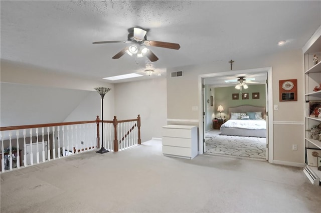 carpeted bedroom featuring a baseboard heating unit, a skylight, and ceiling fan