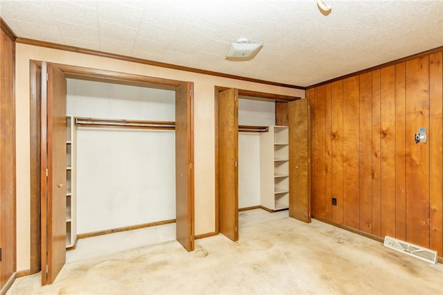 119 Deer Rd, Loyalhanna, PA 15681 - unfurnished bedroom with two closets, ornamental molding, carpet floors, wooden walls, and baseboards