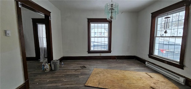 empty room with a baseboard radiator, an inviting chandelier, and dark hardwood / wood-style floors