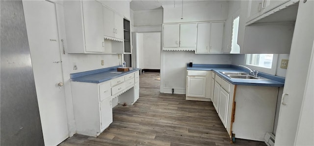 kitchen with dark hardwood / wood-style floors, white cabinetry, a baseboard heating unit, and sink