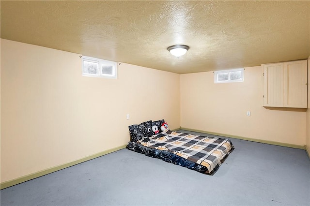 bedroom featuring concrete flooring, a textured ceiling, and multiple windows