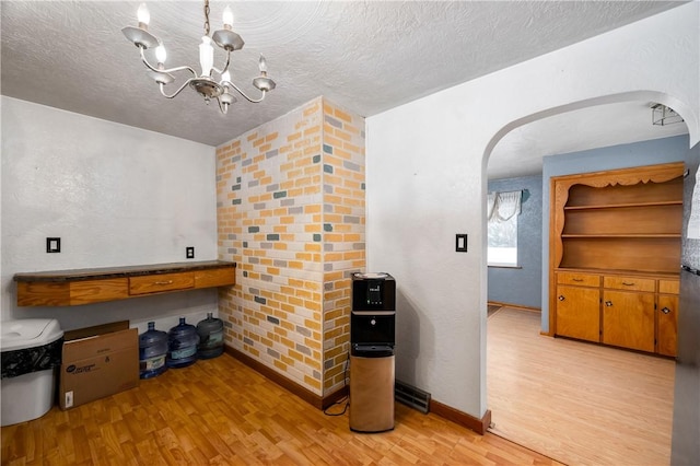 kitchen with a textured ceiling, light hardwood / wood-style floors, and a notable chandelier