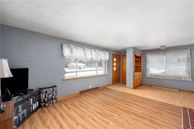 unfurnished living room with a baseboard radiator and light hardwood / wood-style flooring