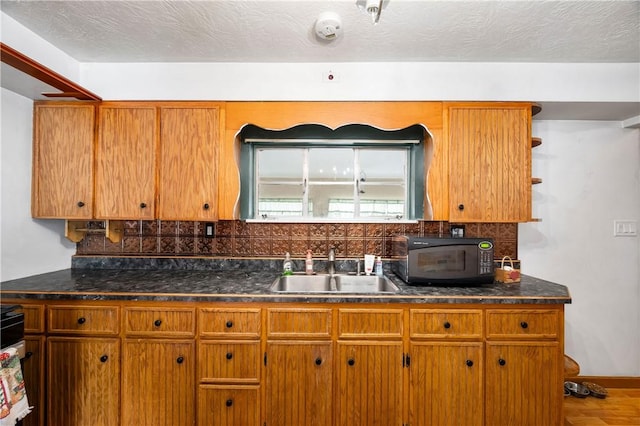 kitchen with tasteful backsplash, wood-type flooring, sink, and a textured ceiling