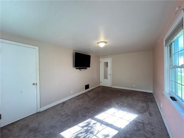 spare room with dark carpet