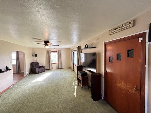 living room with ceiling fan, carpet, and a textured ceiling