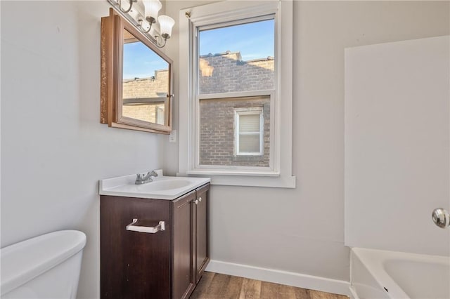 bathroom with a tub to relax in, hardwood / wood-style flooring, vanity, and toilet