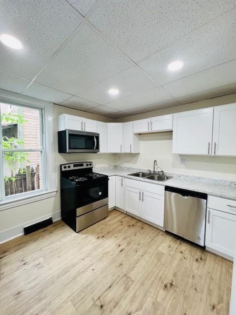 kitchen featuring a drop ceiling, sink, stainless steel appliances, light hardwood / wood-style flooring, and white cabinets