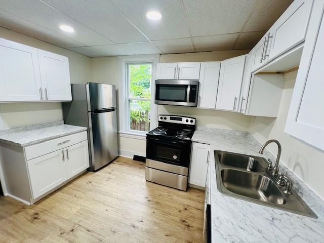 kitchen with white cabinets, a drop ceiling, sink, and appliances with stainless steel finishes