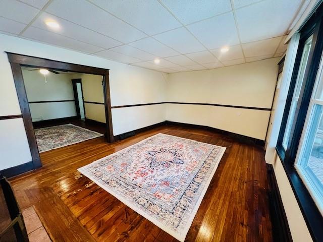 spare room with a paneled ceiling and dark hardwood / wood-style flooring