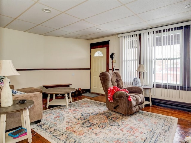 living area featuring hardwood / wood-style flooring and a drop ceiling