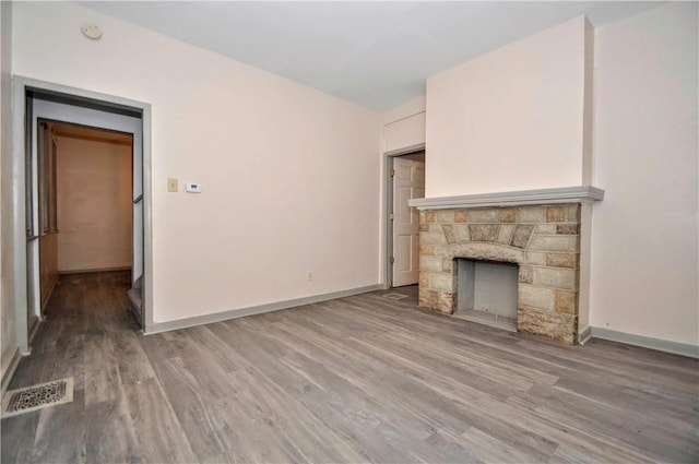 unfurnished living room featuring a stone fireplace and wood-type flooring