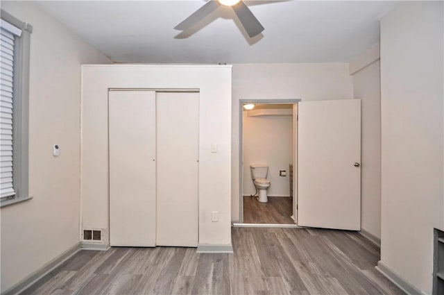 unfurnished bedroom with hardwood / wood-style flooring, ceiling fan, ensuite bath, and a closet