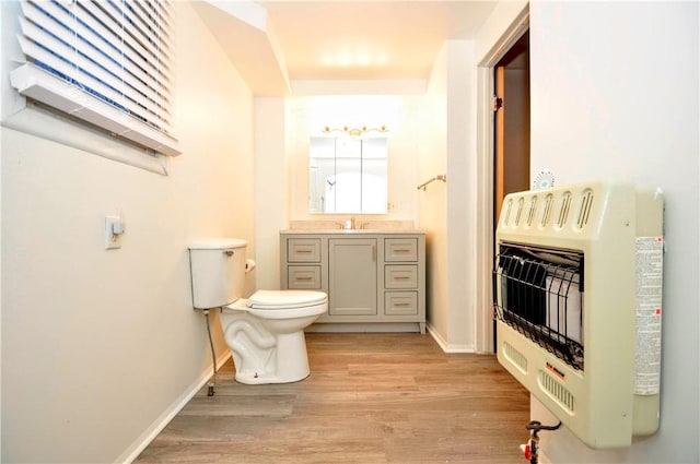 bathroom with heating unit, hardwood / wood-style floors, vanity, and toilet