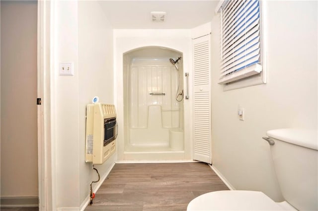 bathroom with hardwood / wood-style floors, heating unit, and toilet