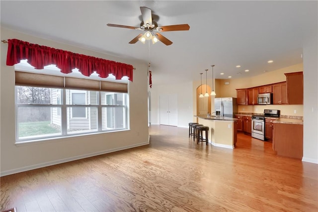 kitchen featuring ceiling fan, a center island, hanging light fixtures, a kitchen breakfast bar, and appliances with stainless steel finishes