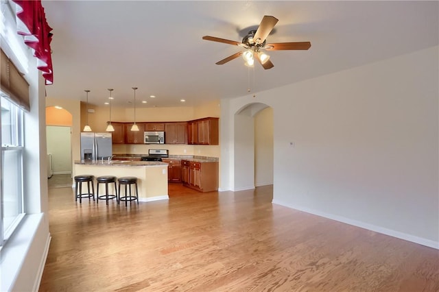 kitchen featuring a breakfast bar, a healthy amount of sunlight, decorative light fixtures, a kitchen island, and stainless steel appliances