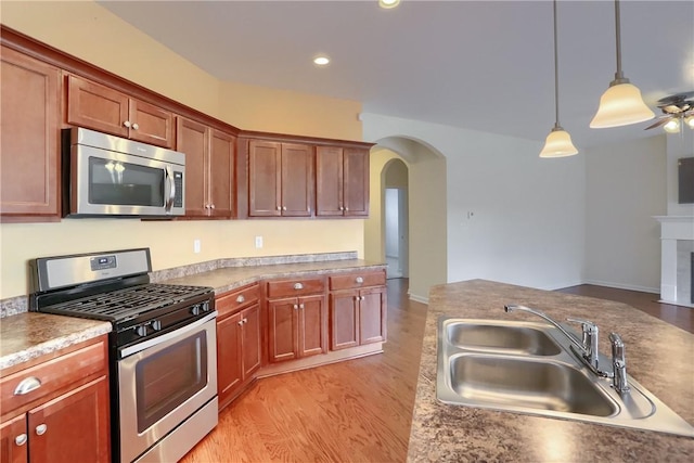 kitchen with sink, light hardwood / wood-style flooring, hanging light fixtures, and appliances with stainless steel finishes