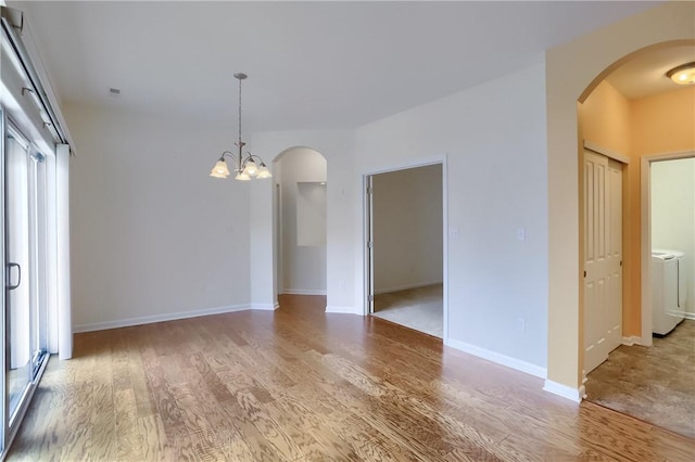 unfurnished room with wood-type flooring, washer / clothes dryer, and an inviting chandelier