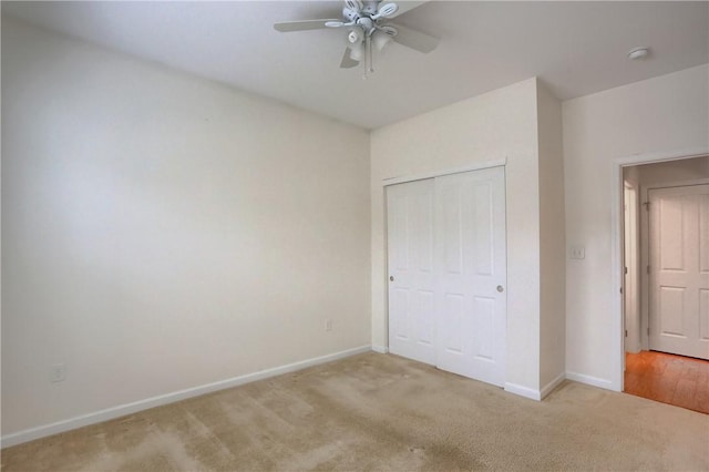 unfurnished bedroom with ceiling fan, a closet, and light carpet