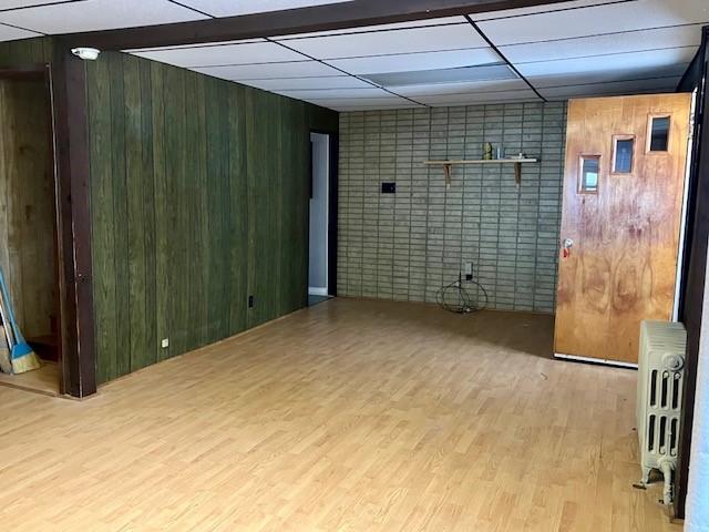 interior space with radiator, a paneled ceiling, wood walls, and hardwood / wood-style flooring