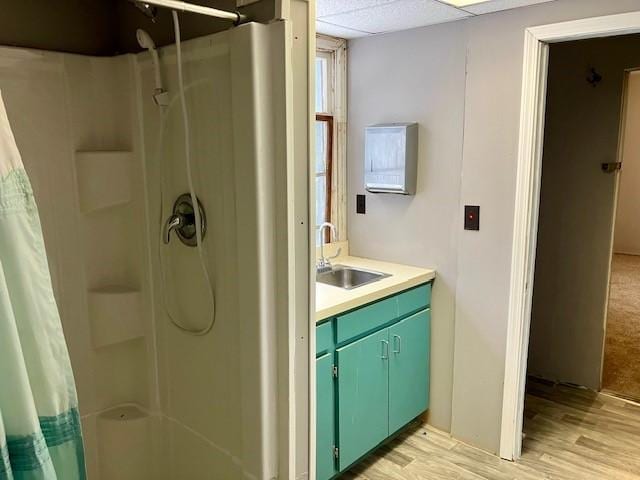 bathroom featuring a shower with shower curtain, vanity, hardwood / wood-style flooring, and a drop ceiling