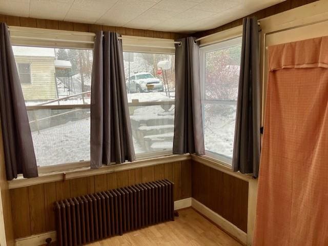 interior space featuring wooden walls, hardwood / wood-style flooring, and radiator