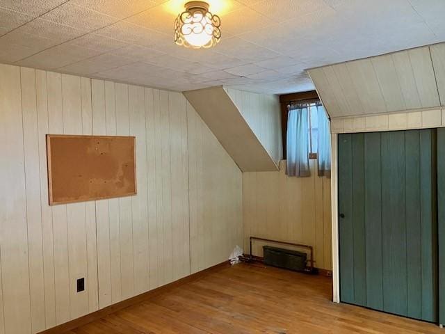 additional living space featuring wooden walls and wood-type flooring