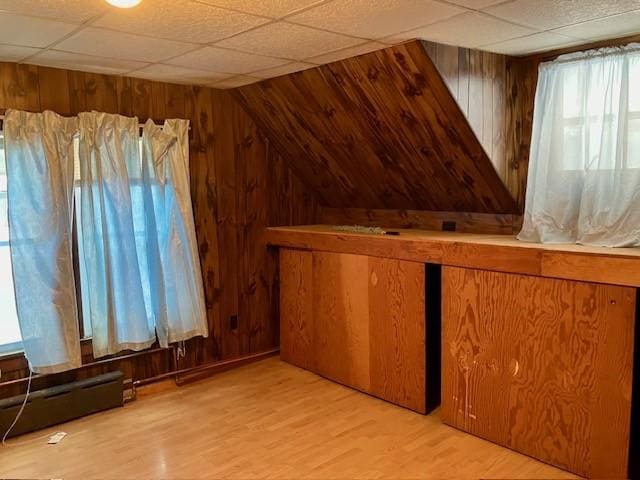 bonus room with light hardwood / wood-style flooring, baseboard heating, and wooden walls