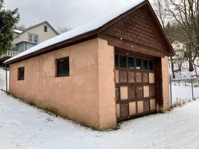 view of snowy exterior with a garage and an outdoor structure