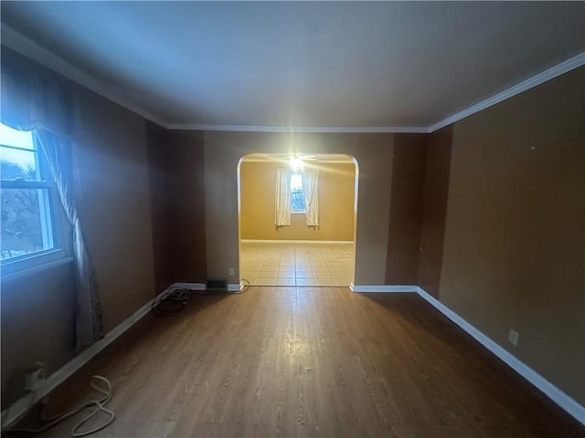 spare room featuring hardwood / wood-style flooring, crown molding, and a healthy amount of sunlight