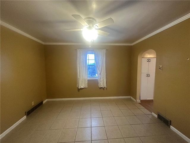 tiled empty room featuring ceiling fan and ornamental molding