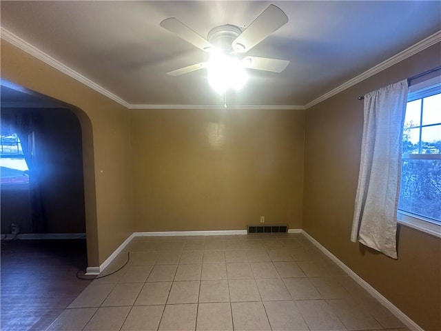 tiled empty room featuring ceiling fan and crown molding