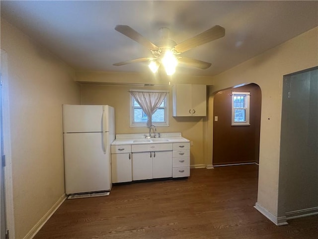 kitchen with ceiling fan, sink, white fridge, white cabinetry, and dark hardwood / wood-style floors