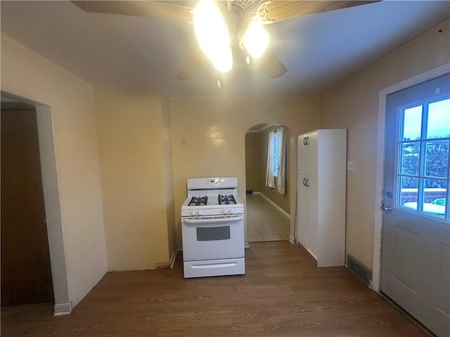 kitchen featuring hardwood / wood-style floors, ceiling fan, and white gas range oven