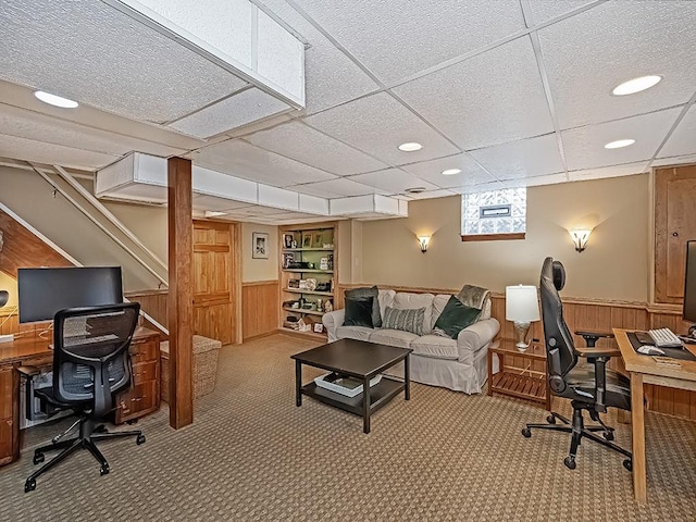 office featuring a drop ceiling, wood walls, and light carpet