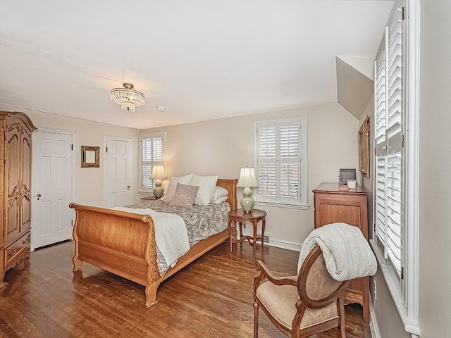 bedroom with a chandelier, multiple windows, and dark wood-type flooring