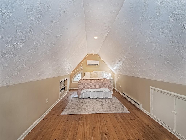 unfurnished bedroom featuring a textured ceiling, a baseboard heating unit, an AC wall unit, hardwood / wood-style floors, and lofted ceiling