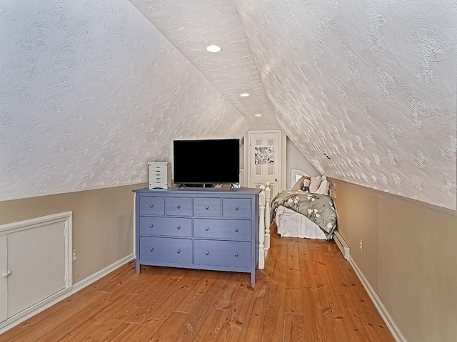 bonus room with a textured ceiling, light hardwood / wood-style floors, and baseboard heating