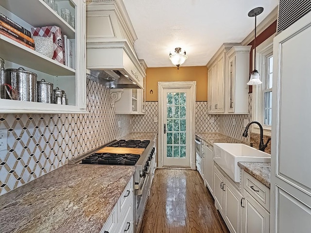 kitchen featuring sink, high end stainless steel range oven, light stone counters, plenty of natural light, and pendant lighting