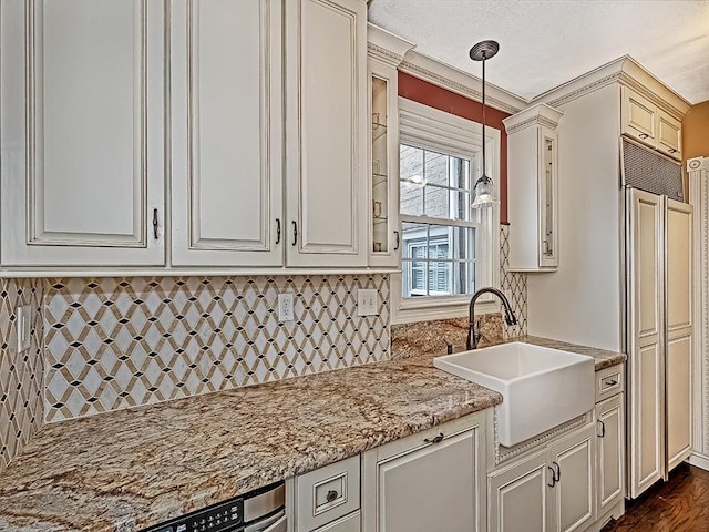 kitchen with light stone countertops, sink, dark wood-type flooring, pendant lighting, and ornamental molding