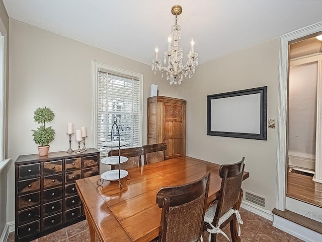 dining area with tile patterned flooring and a notable chandelier