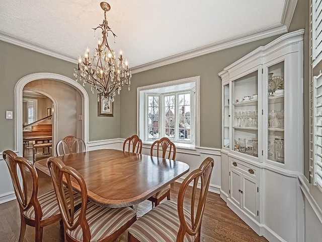 dining space with dark hardwood / wood-style flooring, ornamental molding, and an inviting chandelier