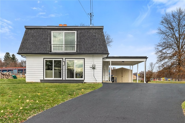 rear view of house featuring a carport, a storage unit, and a lawn