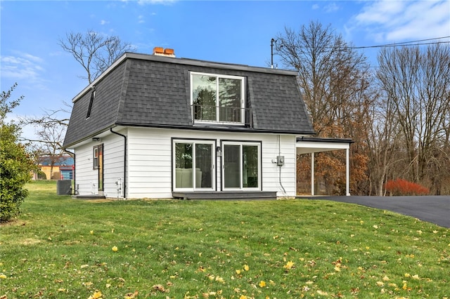 rear view of property with a carport and a lawn