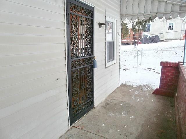 snow covered property entrance with covered porch